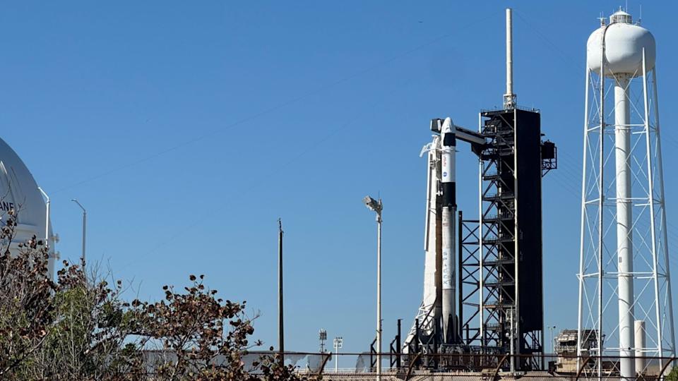 يقف صاروخ SpaceX Falcon 9 بالأبيض والأسود على قمة وسادة للطاقم 10 تحت سماء زرقاء صافية