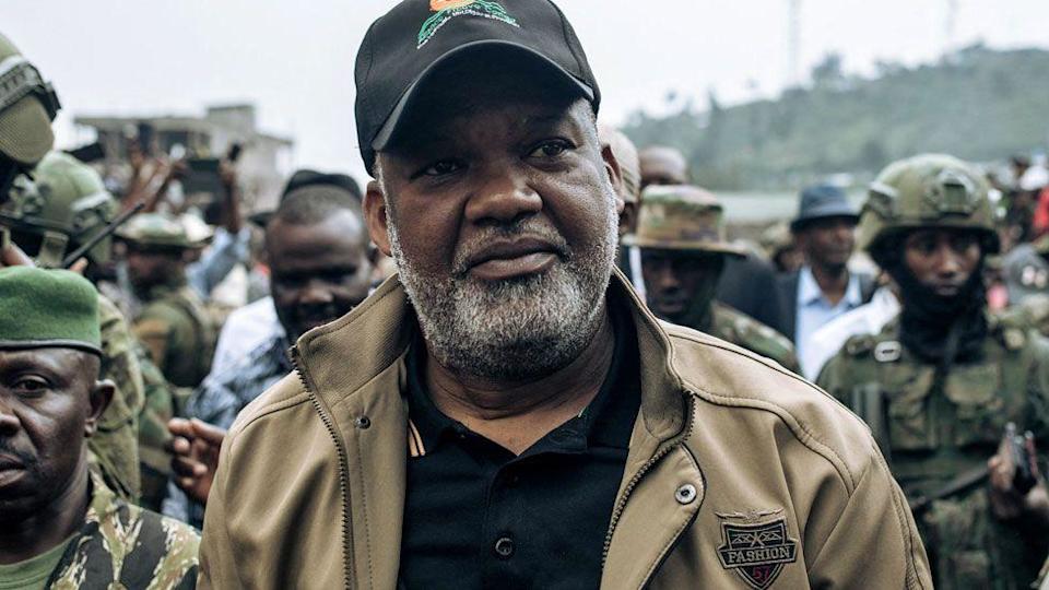 يصل Congo River Alliance Corneille Nangaa ، وهو يرتدي قبعة أسود ، قميص أسود وسترات بنية ، إلى Stade de L'Unite في Goma في 6 فبراير 2025. إنه محاط بمقاتلي M23.
