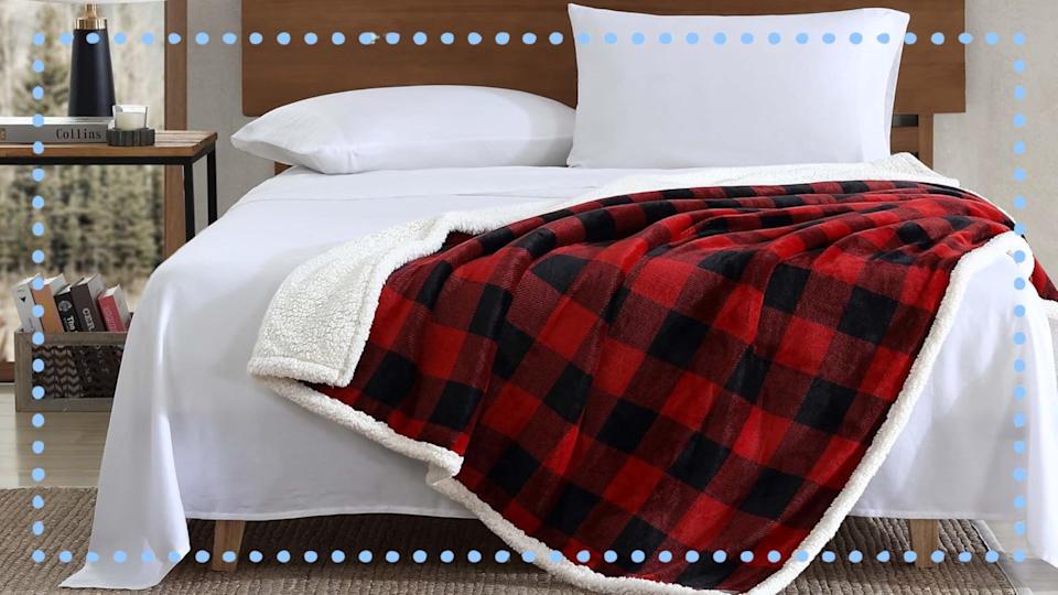 سرير مع بطانية فحص باللونين الأحمر والأسود.