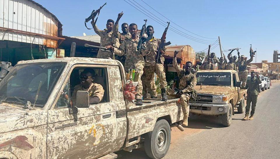 شاحنتان للجيش يحملان جنودًا يهتفون ينتمون إلى الجيش السوداني في شارع في شمال الخرطوم - مارس 2025