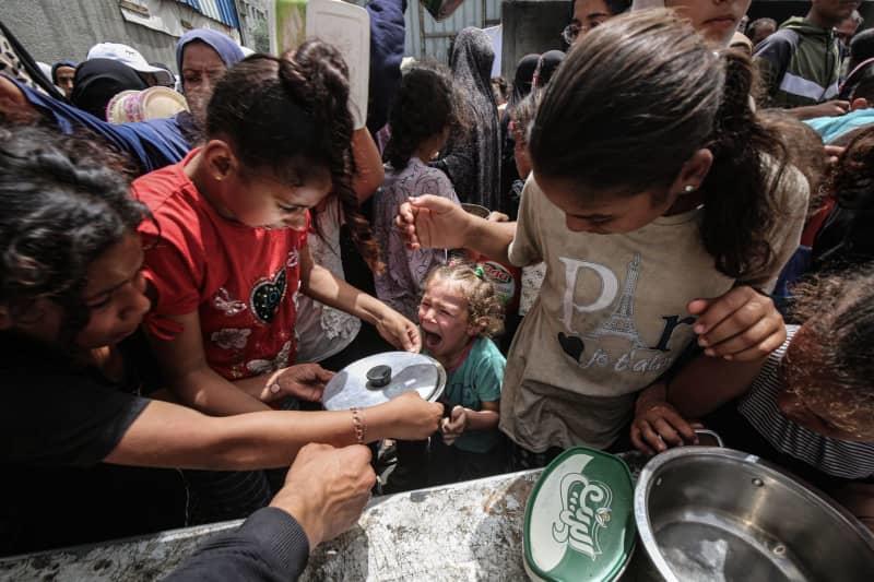 ينتظر الفلسطينيون أمام نقطة توزيع الطعام المجانية لتلقي جزءهم من الوجبة الساخنة ، في معسكر Nusiirat للاجئين في قطاع غزة الوسطى. عمر Ashtawy/APA عبر Zuma Press Wire/DPA