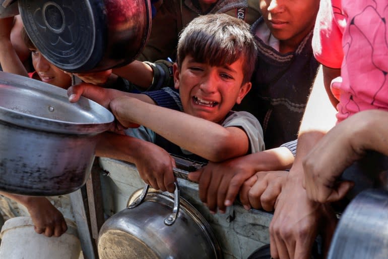 يصرخ أطفال فلسطينيون بينما يتجمع الناس لتلقي الطعام في غزة
