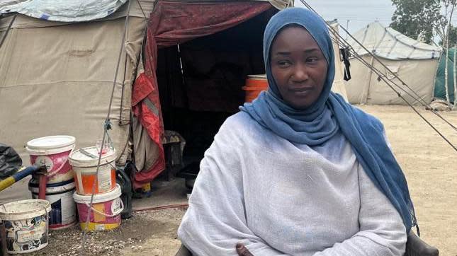 يجلس حنا أمام خيمة في معسكر للنزوح في بورت السودان.