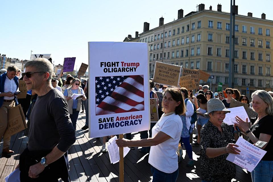يحمل المتظاهر علامة مع "Fight Trump Aligarchy ، Save American Democracy" المكتوبة عليها في ليون ، فرنسا.