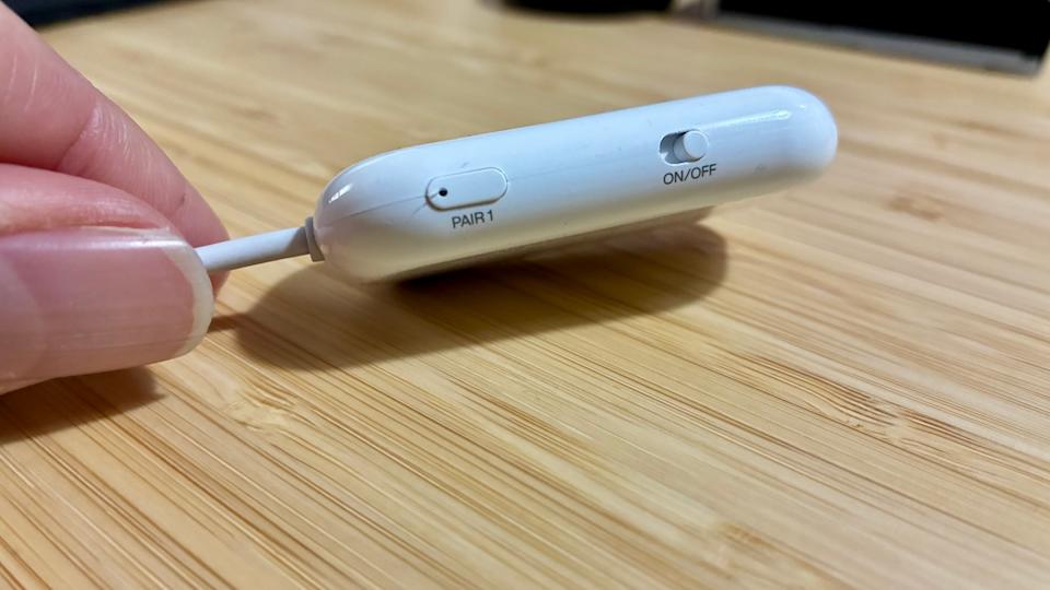 عرض جانبي لـ Airfly Pro 2 ، يُظهر مفتاح التشغيل/إيقاف تشغيله وواحد من أزرار الاقتران.