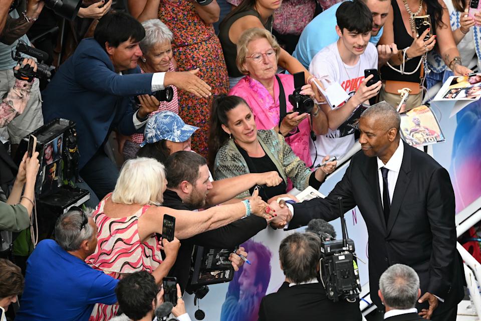 Denzel Washington يهز يد مروحة قبل العرض.