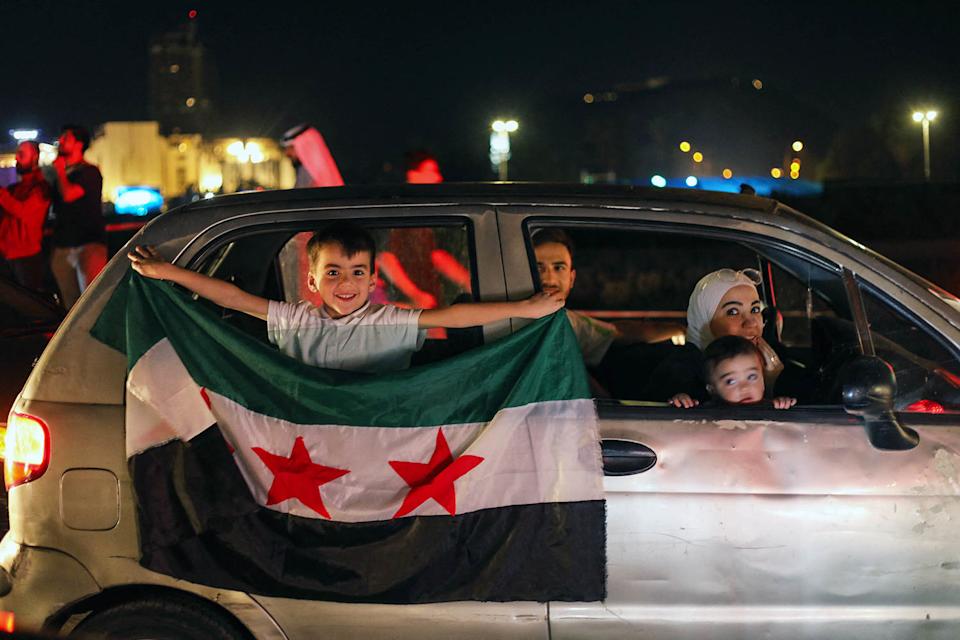 صبي صغير يحمل علمًا سوريا من سيارة في ميدان أومياد في دمشق (عبد العزيز كيتاز / AFP عبر Getty Images)