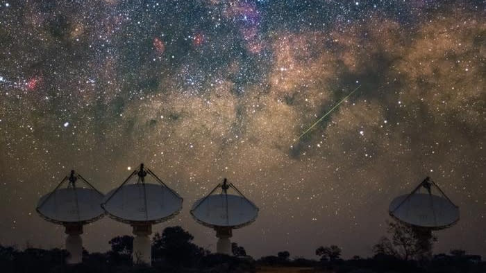 يتكون تلسكوب راديو ASKAP من CSIRO من 36 طبقًا منتشرة عبر 6 كيلومترات في Wajarri Country - أربعة أطباق من الأقمار الصناعية ، ثلاثة على اليسار ، وواحد على اليمين ، تشير إلى أعلى نحو سماء ليلية بالنجوم.