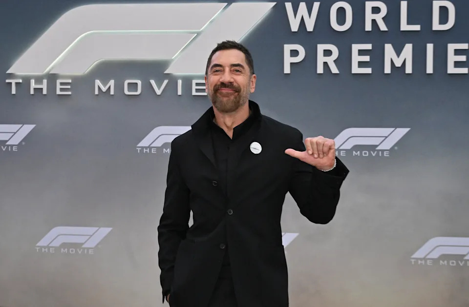 يشير Javier Bardem إلى دبوسه وهو يقف أمام خطوة وتكرار يقرأ F1: الفيلم.