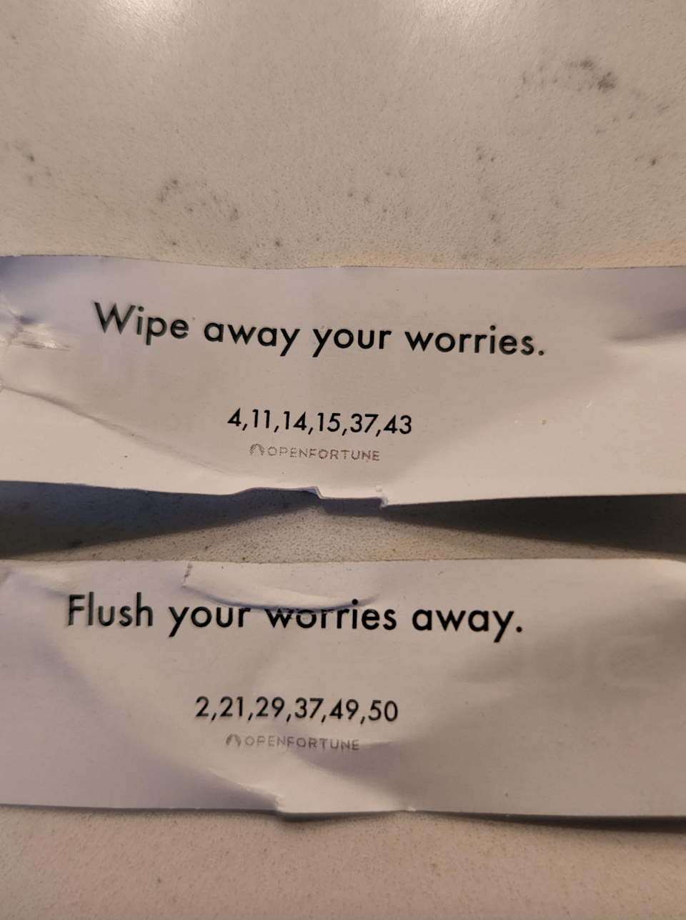 اثنين من ملفات تعريف الارتباط Fortune يزحدران بأقوال: "امسح مخاوفك" و "قم بتدفق مخاوفك بعيدًا" ، تليها أرقام اليانصيب
