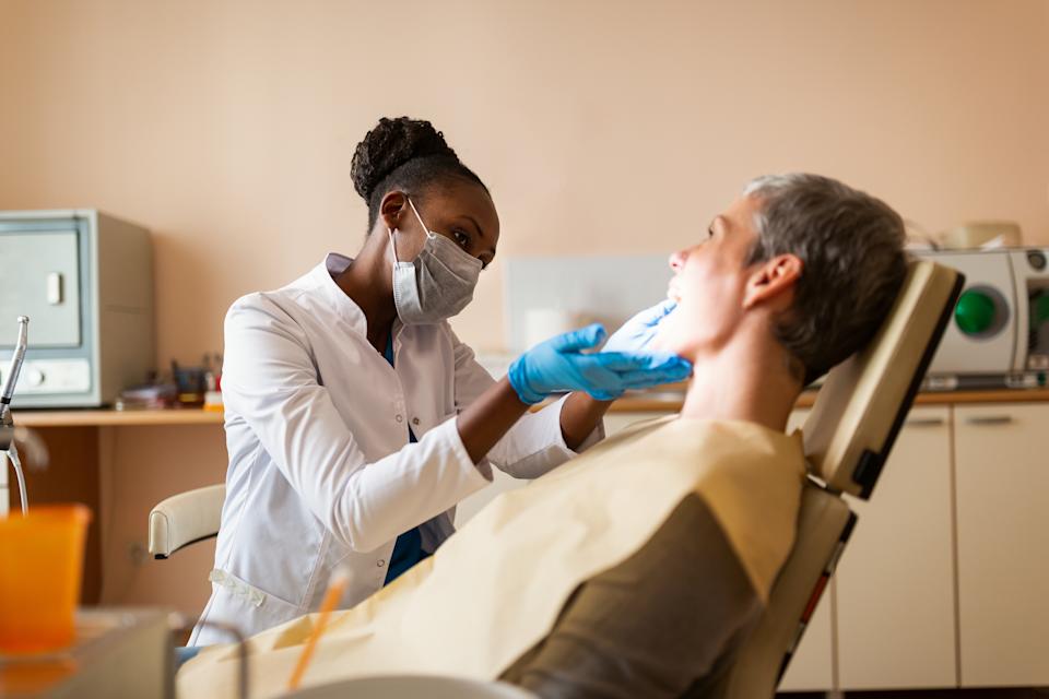يفحص طبيب الأسنان مريضًا مبتسمًا في مكتب طب الأسنان ، ويعزز الرعاية الصحية عن طريق الفم