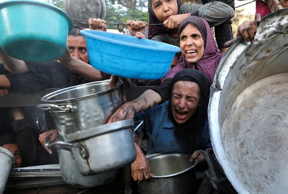 يطلب الفلسطينيون الطعام من مطبخ خيري في مدينة غزة (رويترز)