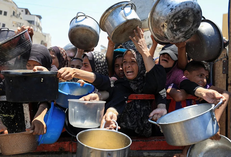 يجتمع الفلسطينيون لتلقي الطعام من مطبخ خيري ، وسط أزمة جوع ، في مدينة غزة (رويترز)
