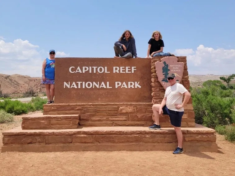 يجلس Kosters ويقفون حول علامة حديقة Capitol Reef الوطنية.