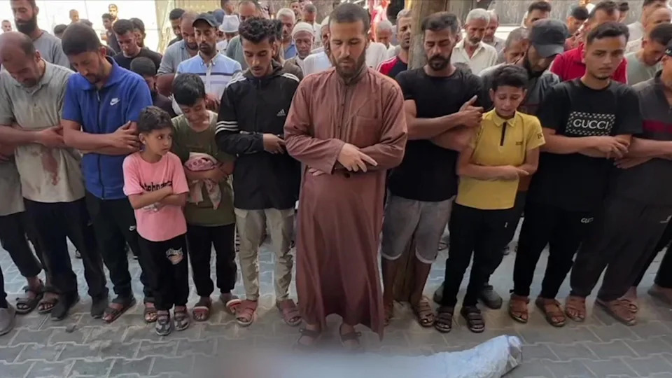 يصلي الرجال والأولاد بجانب جثة طفل قتل في ضربة جوية إسرائيلية ضربت نقطة توزيع المياه في 13 يوليو 2025