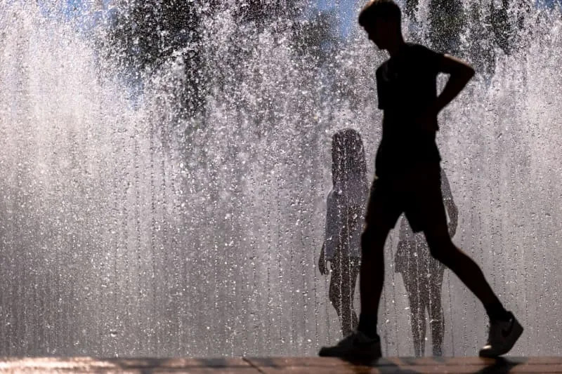 يسير الشباب عبر تركيب المياه "جناح المياه السداسية" للفنان الدنماركي Jeppe Hein أمام متحف Neues. يعد التثبيت في شكل نافورة مشية وسيلة شائعة للتبريد في درجات حرارة الصيف. دانييل كارمان/دبي