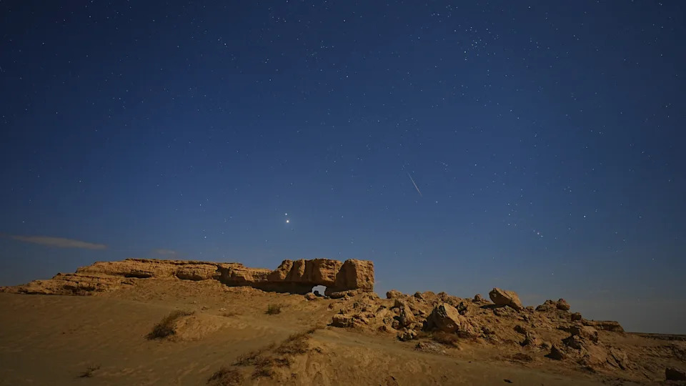 تم تصوير النيزك في سماء ليلة النجوم فوق نتوء صخري.