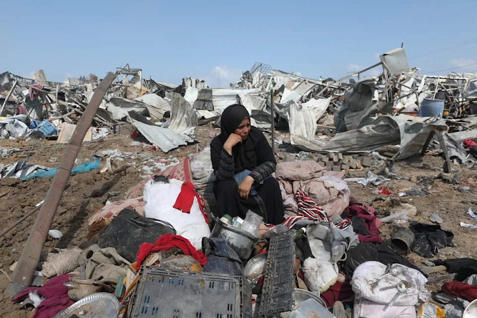 امرأة فلسطينية تجلس مع ممتلكاتها بعد ضربة إسرائيلية في معسكر للمنزل الداخلي في دير بالا ، في قطاع غزة وسط (AFP/Getty)