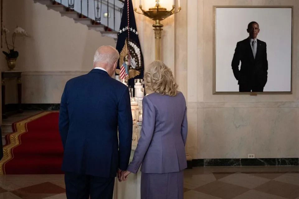 يقف Bidens بجانب صورة باراك أوباما في البيت الأبيض.