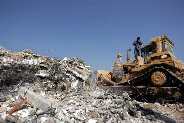 KFAR DAROM ، GAZA Strip - 30 أغسطس: يقوم جرافة هدم المنازل في 30 أغسطس 2005 في مستوطنة KFAR DAROM في قطاع غزة. بعد الانسحاب الإسرائيلي من غزة الذي أزال حوالي 9000 مستوطن يهودي من 21 مستوطنة في غزة وأربعة في الضفة الغربية الشمالية ، يقوم الجيش الإسرائيلي الآن بهدم جميع المستوطنات ويتوقع أن يغادر قطاع غزة في الأسابيع المقبلة. (تصوير ماركو دي لورو/غيتي إيمايز)