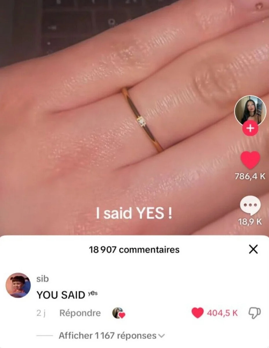 يد مع حلقة بسيطة ونص تراكب "قلت نعم!" أدناه ، تعليق Tiktok يقول "قلت نعم" مع العديد من الإعجابات