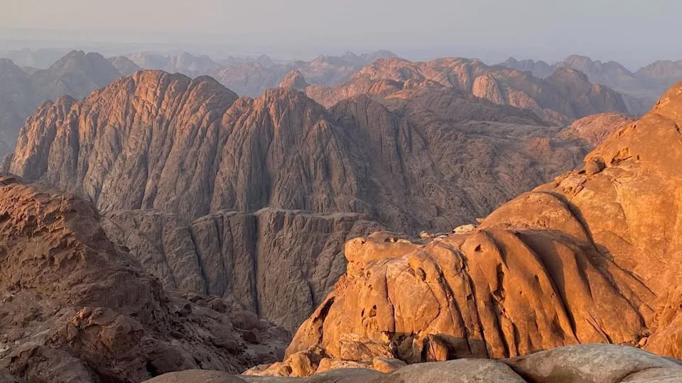 الجبال في الغسق ، من Jebel El Ahmar في عام 2024. Light يضرب الجزء العلوي من سلسلة جبال صخرية ، والتي تمتد إلى المسافة
