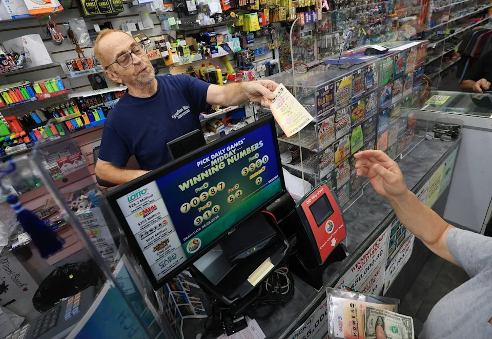 Joe Raedle/Getty Images - الصورة: يبيع Robert Hadad تذاكر Powerball Lottery لعميل في متجره في وسط مدينة ميامي في 26 أغسطس 2025 في ميامي ، فلوريدا.