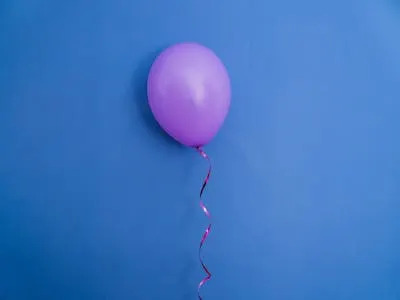 بالون أرجواني مهب على خلفية زرقاء.