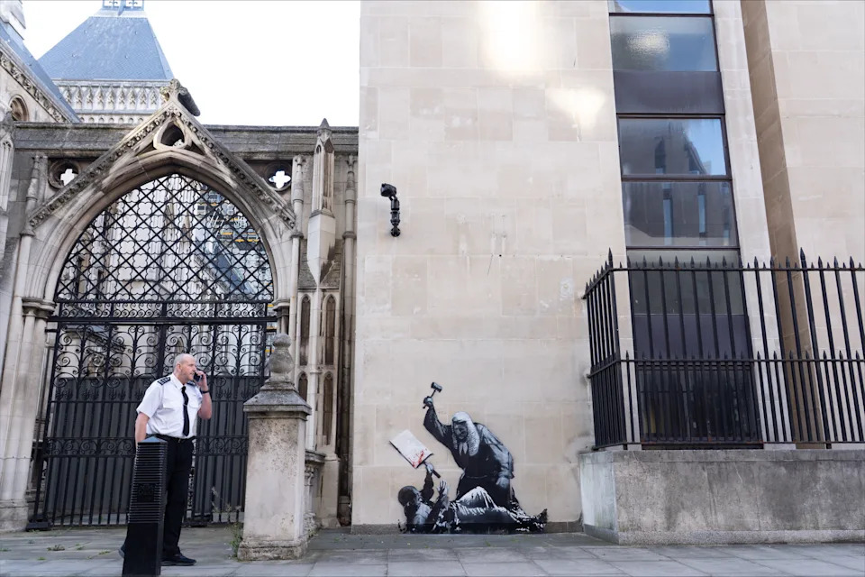 صورة غير مؤرخة صادرة عن Banksy من العمل الفني الجديد للفنان الذي يظهر قاضًا يهاجم متظاهرًا بمسافرة في محاكم العدل الملكية في لندن والتي تم تغطيتها بالفعل. تم إخفاء العمل الفني ، الذي يقع على جدار خارجي لمبنى الملكة ، وهو جزء من مجمع المحاكم الملكية للعدالة ، بواسطة صفائح كبيرة من البلاستيك الأسود وحواجز معدنيين. تاريخ الإصدار: الاثنين 8 سبتمبر ، 2025. يجب أن تقرأ رصيد الصورة: Banksy/Pa Wire Note للمحررين: لا يجوز استخدام صورة البيان هذه إلا لأغراض الإبلاغ التحريري للتوضيح المعاصر للأحداث أو الأشياء أو الأشخاص في الصورة أو الحقائق المذكورة في التسمية التوضيحية. قد تتطلب إعادة استخدام الصورة المزيد من الإذن من حامل حقوق الطبع والنشر.