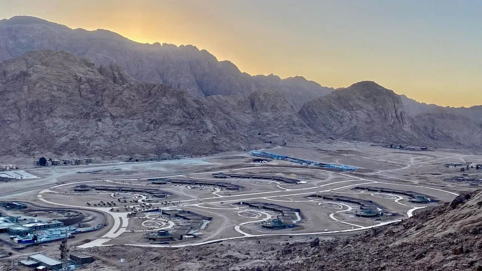 منظر لأحد التطورات ، لا يزال قيد الإنشاء سهل في الرحا. تشرق الشمس خلف الجبال المحيطة ، في حين أن موقع التطوير في المقدمة ، مع طرق تربط المباني المختلفة