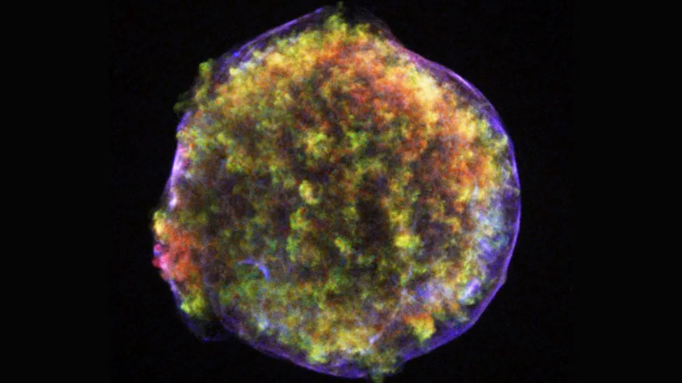 تُظهر سحابة من الغاز البرتقالي والأصفر داخل حلقة من اللون الأرجواني بقايا انفجار supernova في الفضاء العميق.