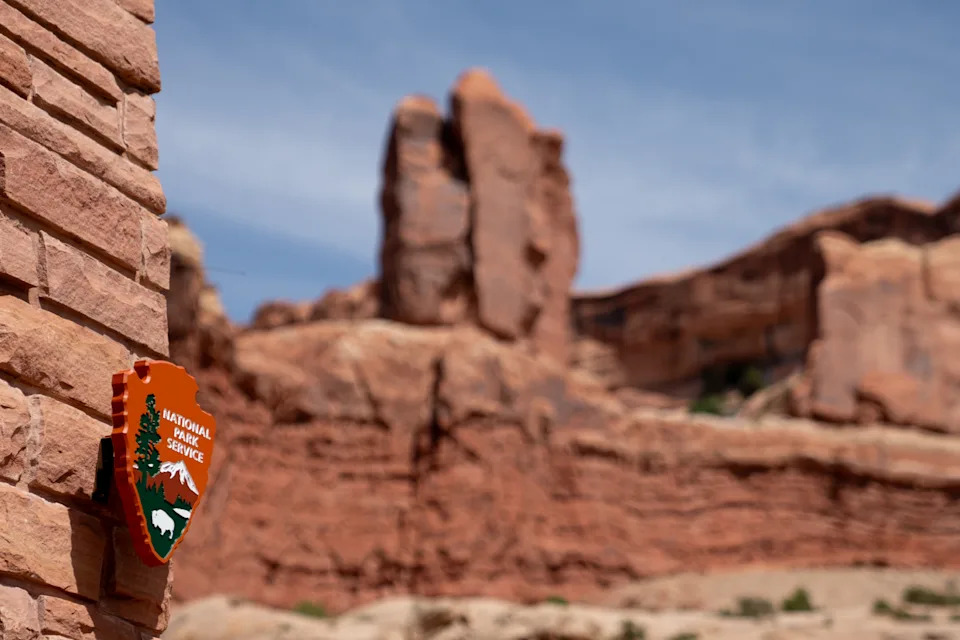 خدمة National Park Service على جدار حجري مع تشكيلات صخرية مرئية في الخلفية