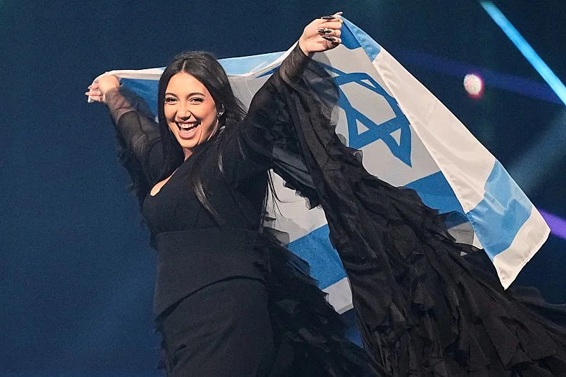 المغني يوفال رافائيل من إسرائيل يحمل العلم الوطني خلال بروفة لمسابقة الأغنية الأوروبية في بازل، 16 مايو 2025