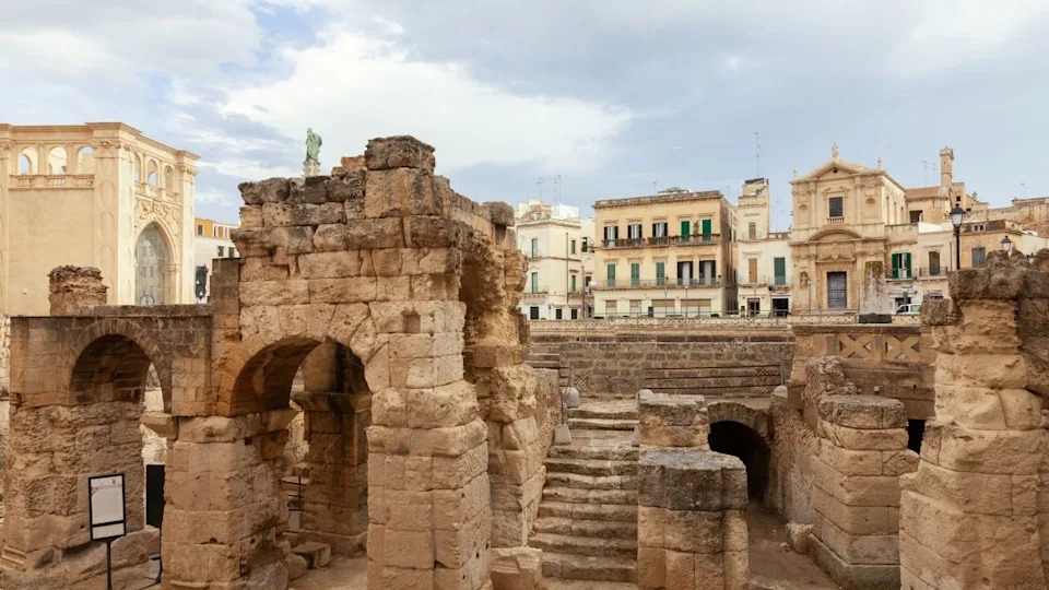 لقطة جوية للمباني الخارجية الجرونج مع بوابات مقوسة حجرية قديمة ذات لون أزرق خبيث في ليتشي، إيطاليا