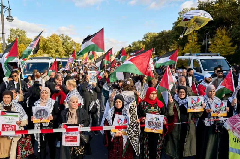 متظاهرون يلوحون بالأعلام الفلسطينية ويحملون ملصقات خلال مسيرة