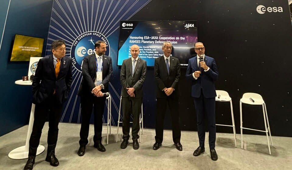 يقف خمسة رجال يرتدون بدلات مظلمة أمام جدار أزرق غامق مع شعار وكالة الفضاء الأوروبي على ذلك