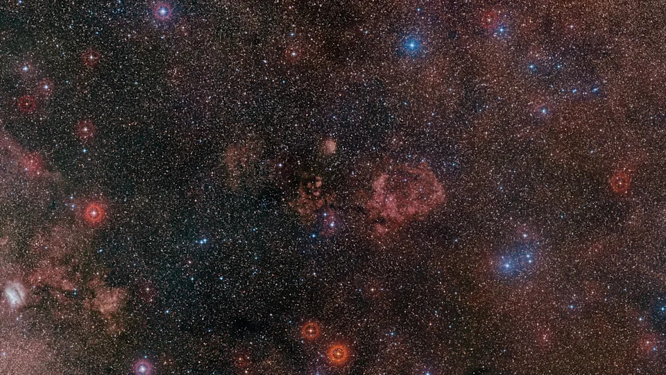 تم تصوير مشهد في الفضاء السحيق يضم سحبا سديمية حمراء متوهجة تشكل الخطوط العريضة لجسم الخفافيش وأجنحته، مربوطة بخيوط داكنة من الغاز بين النجوم مقابل حقل نجمي مزدحم.