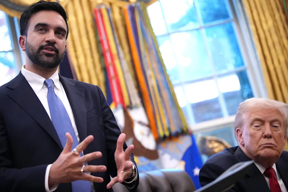 رجلان في غرفة رسمية، أحدهما يتحدث بحركات اليد والآخر جالس ويستمع بانتباه