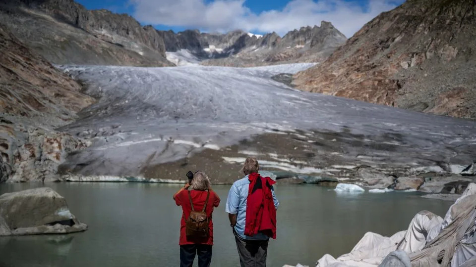 سائحان يواجهان نهر الرون الجليدي الذائب في 12 سبتمبر 2025. تتأثر الأنهار الجليدية في سويسرا بشكل غير متناسب بتغير المناخ، وقد فقدت ربع كتلتها في العقد الماضي وحده. - فابريس كوفريني / وكالة الصحافة الفرنسية / غيتي إيماجز