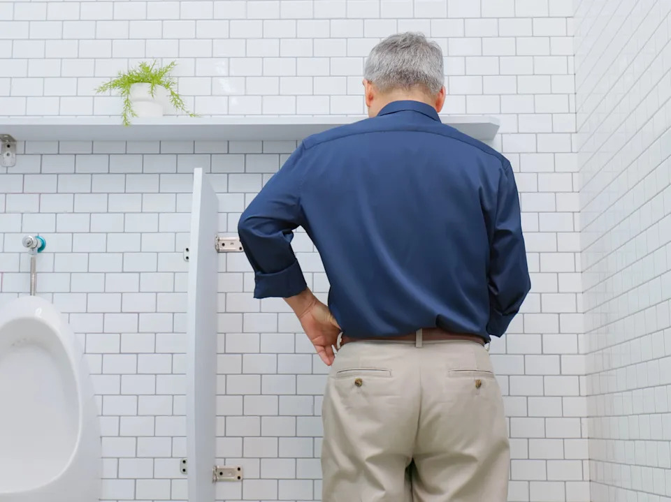 مفهوم أمراض الجهاز البولي التناسلي لدى الذكور - رجل مسن آسيوي سعيد يتبول بسلاسة في الحمام