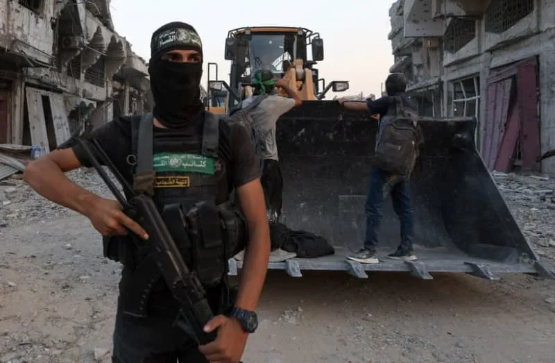 إرهابي من حماس يقف بجوار آلات ثقيلة، بعد أن قالت حماس إنها عثرت على بقايا رهينة إسرائيلية يوم الثلاثاء وتستعد لإعادتها إلى إسرائيل من خلال الصليب الأحمر، في مدينة غزة، 4 نوفمبر، 2025. (REUTERS/DAWOUD ABU ALKAS)