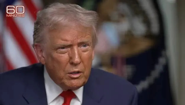 شخص مجهول الهوية يجلس في مكان المقابلة مع تعبير جدي، "60 دقيقة" مرئية في زاوية الصورة