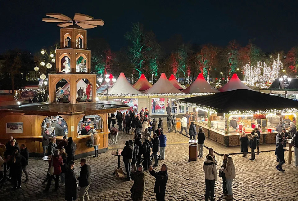 صور بزاوية عالية لسوق عيد الميلاد في برلين. يقف الناس عند الأكشاك الخشبية 