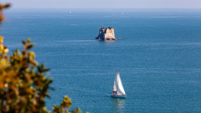 مركب شراعي في الماء مع برج حجري في البحر