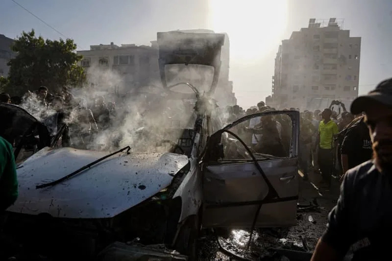 فلسطينيون وطواقم الدفاع المدني ينتشلون شهداء استشهدوا في غارة جوية إسرائيلية استهدفت سيارة في منطقة العباس غرب مدينة غزة. عمر أشتاوي/APA الصور عبر ZUMA Press Wire/dpa