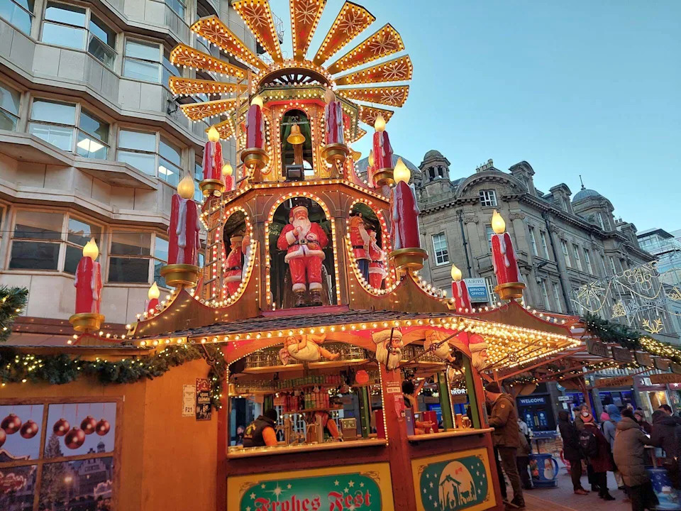 كشك لبيع الكحول في سوق عيد الميلاد. تم تزيين الكشك الخشبي بأضواء ذهبية وشموع حمراء وهمية عملاقة وجرس وزخارف سانتا