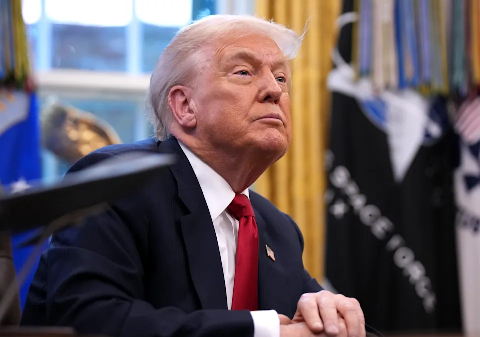 شخص يرتدي بدلة يجلس على مكتب، ويبدو مفكرًا، في مكتب به عناصر زخرفية في الخلفية