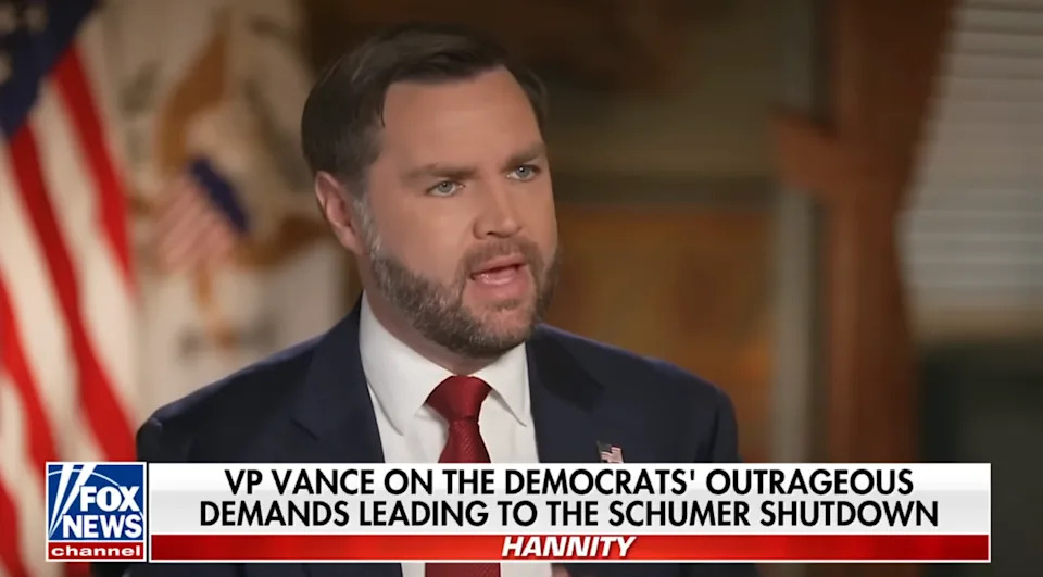 يظهر رجل يرتدي بدلة وربطة عنق على قناة إخبارية يناقش القضايا السياسية المتعلقة بإغلاق الحكومة