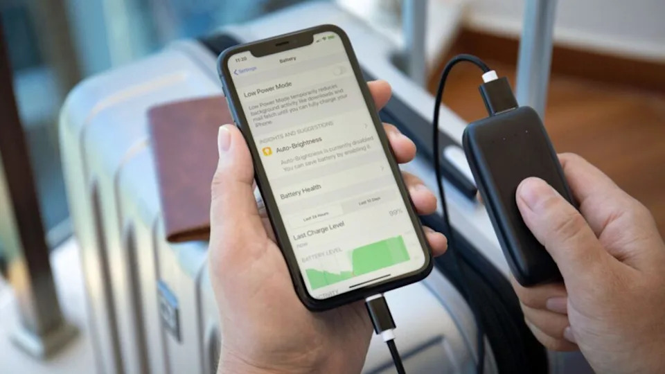 ألانيا، تركيا. رجل يحمل Powerbank RavPower وiPhone 11 مع تطبيق البطارية على الشاشة