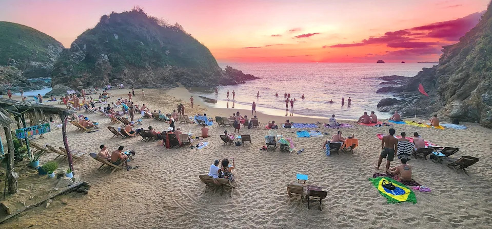 زيبوليت، المكسيك - 3 أبريل 2025: السباحون يسترخون عند غروب الشمس على الشاطئ في بلايا ديل أمور